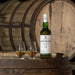 Whisky In Two Glasses With A Bottle Of Laphroaig 15 Year Whisky On Barrel In Distillery