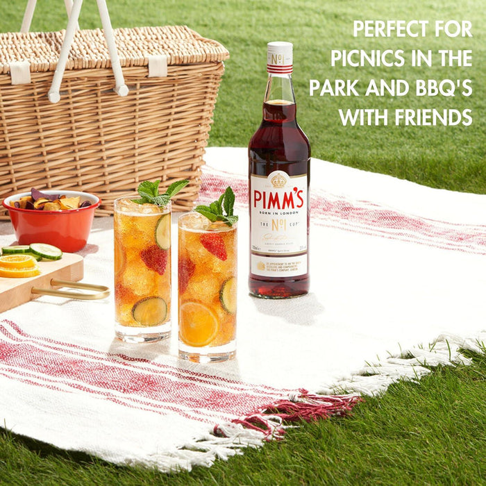 Pimm's bottle with two glasses of cocktails on a picnic blanket in the park