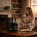 Woman sitting in a cosy room with a bottle of Kopke 10 Year Old Tawny Port and glasses