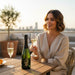 Woman sitting at a table with a bottle of 1Evolution 1276 Blanc De Blancs and two glasses
