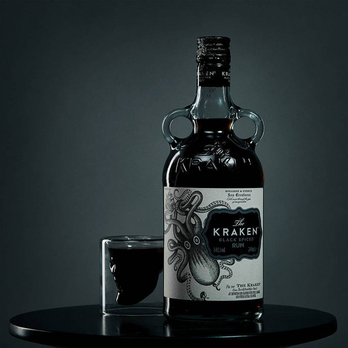 Bottle of The Kraken rum with a glass on a dark background