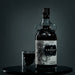 Bottle of The Kraken rum with a glass on a dark background