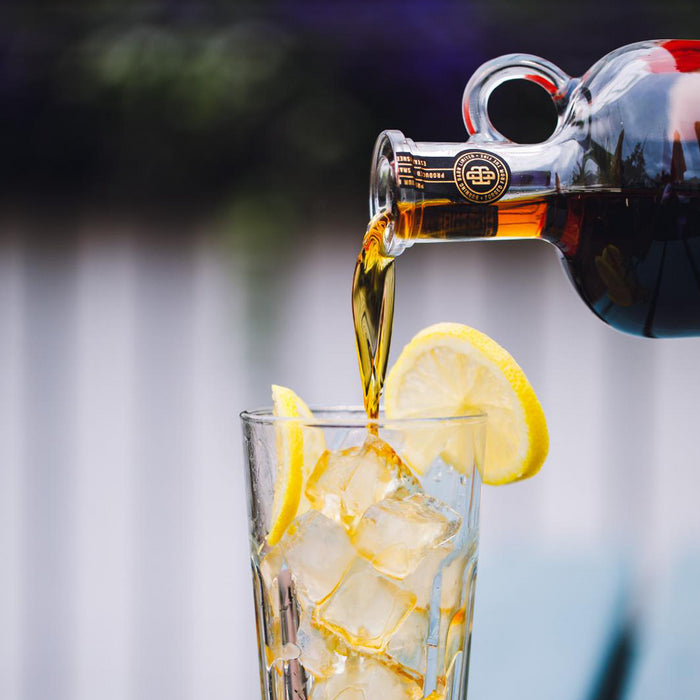 Bottle of rum  being poured into a glass with ice and lemon slices