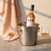 Bottle of AIX wine in an ice bucket with two glasses on a table.