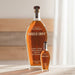Bottle of Angels Envy bourbon whiskey on a wooden surface with a neutral background