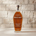 Bottle of Angels Envy bourbon whiskey against a stone wall background