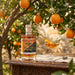 Chalice Mead bottle with a cocktail in an outdoor setting with oranges and flowers.