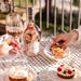 Bottle of Rosé wine with a glass and snacks on a table outdoors.