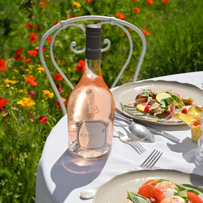 Bottle of Rosé wine on a table with a plate of salad in a garden setting