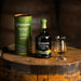 Connemara Peated Single Malt Irish Whiskey bottle, gift tube and tasting glass on an ex-bourbon oak barrel