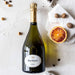 Bottle of Dom Ruinart 2010 Champagne infront of a Chalk stone background next to hazelnuts and lemons