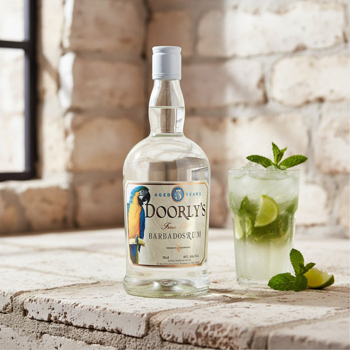 Doorly's Barbados rum bottle with a cocktail garnished with lime and mint leaves on a stone surface.