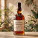 A bottle of Foursquare Rum Distillery Secret Bottle Shop 1751, 14 Years Old, filled with amber liquor, set on a wooden table with a warm, blurred background of plants and light.