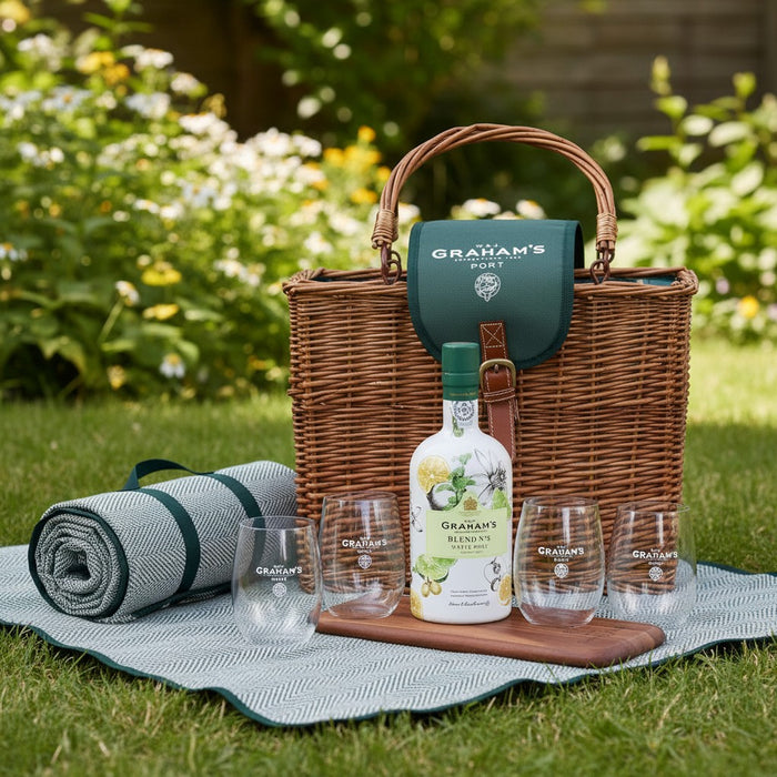 Grahams picnic hamper full set with basket, bottle of port, glasses, picnic rug and chopping board on grass