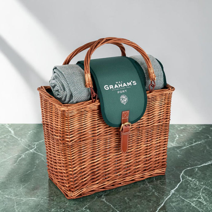 Wicker picnic basket with a green blanket and 'Graham's' branding on a marble surface.