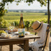Wine bottle with a glass of white wine on a table in a vineyard setting