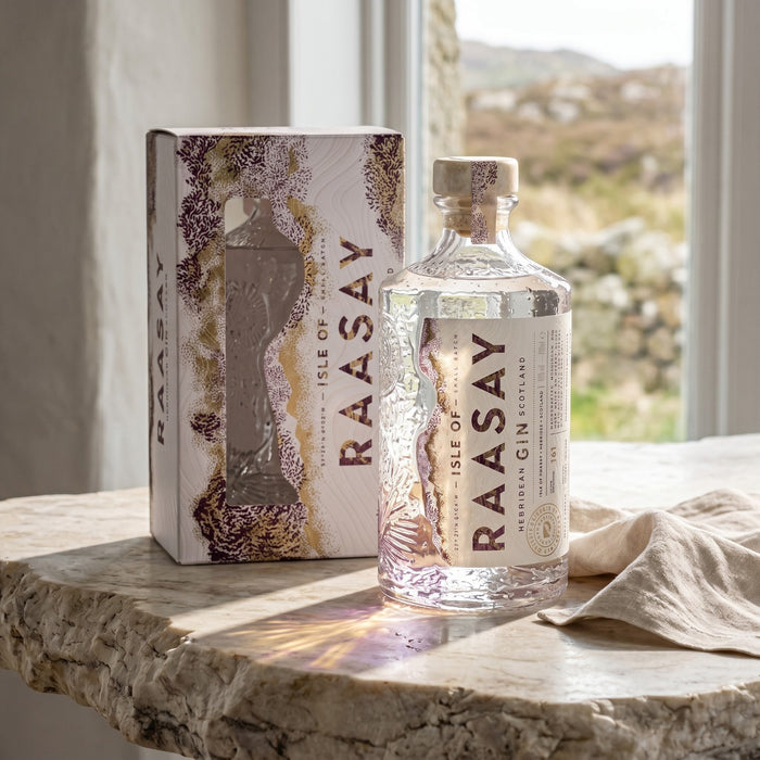 Raasay Gin bottle and box on a stone surface with a scenic background