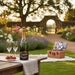 Bottle of Laborie champagne with two glasses and a picnic basket in a garden setting.