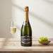 Bottle of Laborie champagne with a glass and grapes on a wooden table