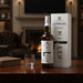 Laphroaig whisky bottle and packaging on a wooden table with a fireplace in the background