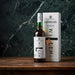 Bottle and box of Laphroaig whisky on a wooden surface with a dark marble background