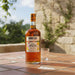 Mount Gay Spiced rum bottle with a glass on a stone table outdoors.