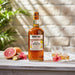 Mount Gay Spiced rum bottle with two glasses on a wooden table outdoors.