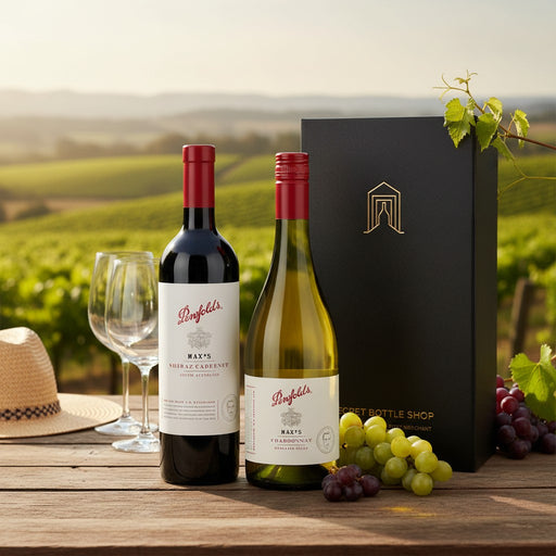 Two wine bottles with a box and grapes on a wooden table with a vineyard background