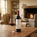 Penfolds wine bottle with a glass on a wooden table in a cozy living room.