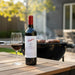 Penfolds wine bottle with a glass on a wooden table outdoors