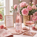 Rozel Rose Vodka with pink flowers in a home setting, with cocktails and sweet treats