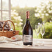 Bottle of Savian Prosecco Rosé with two glasses on a wooden table outdoors.