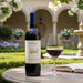 Seghesio Zinfandel wine bottle with a glass of red wine on a table outdoors.