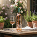 BottleChateau d'Estoublon Source de Roseblood Provence Rose wine with a glass on a wooden table outdoors.