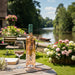 Bottle ofChateau d'Estoublon Source de Roseblood Provence Rose wine with a glass on a wooden table in a garden setting.