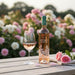 Bottle of 'Chateau d'Estoublon Source de Roseblood Provence Rose wine with a glass on a wooden table in front of flowers