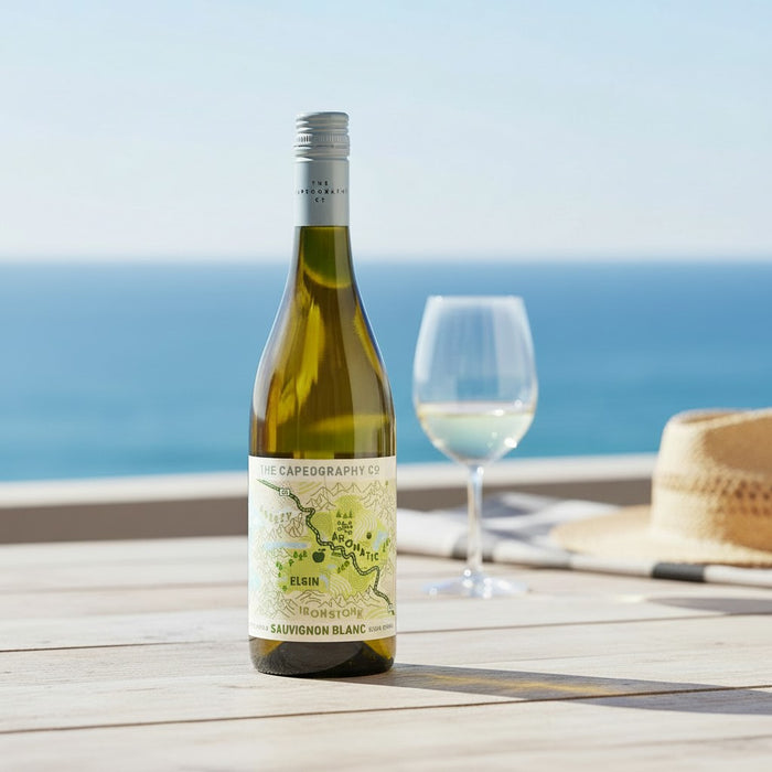 Bottle of white wine with a glass on a wooden table by the ocean