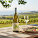 Bottle of white wine and glass on a table with a scenic vineyard background