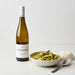 Bottle of Two Rivers Riesling wine next to a bowl of curry with rice on a white background