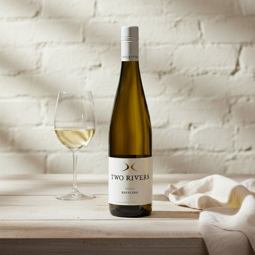 Bottle of Two Rivers Riesling wine with a glass on a wooden surface.