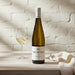 Bottle of Two Rivers Riesling wine with a glass on a wooden surface.