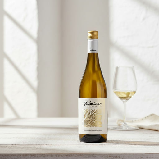 Bottle of Valmioner white wine with a glass on a light wooden surface.