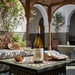Bottle of Valmeinier white wine with a glass on a decorative table in an outdoor setting.