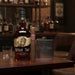 Buffalo Trace whiskey bottle with a cigar and flask on a bar counter.