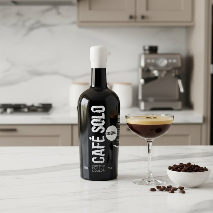 Bottle of Cafe Solo coffee liqueur on a kitchen counter with a glass of coffee liqueur and bowl of coffee beans.