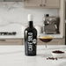 Bottle of Cafe Solo coffee liqueur on a kitchen counter with a glass of coffee liqueur and bowl of coffee beans.