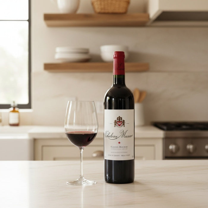 Bottle of Château Musar red wine with a glass on a kitchen counter