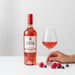 Bottle of Domaine de La Begude rosé wine with a glass of wine and berries on a white background