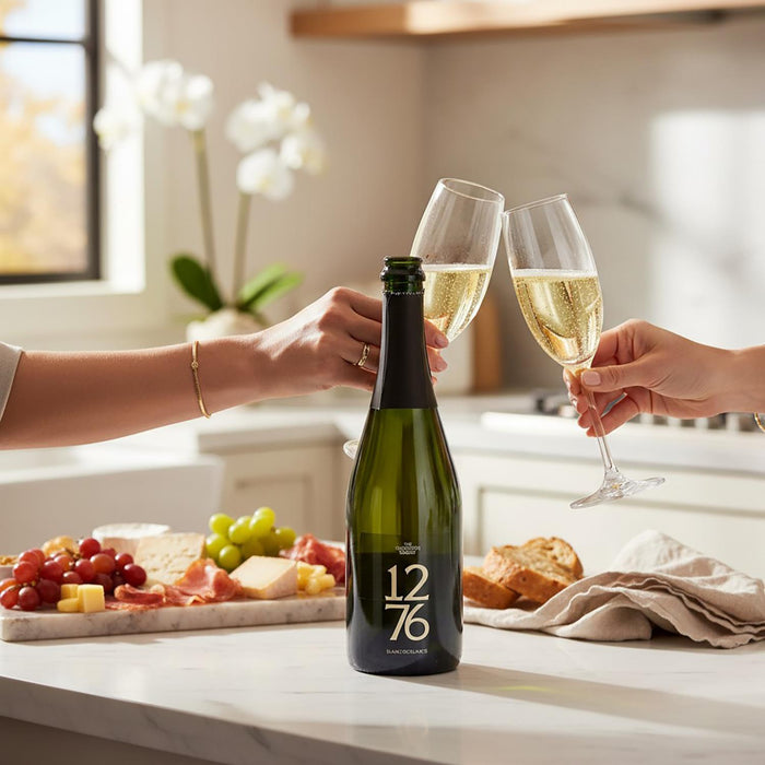 Two people clinking champagne glasses with a bottle of Evolution 1276 Blanc De Blancs