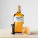 Highland Park whisky bottle with a glass of cocktail and jigger on a light background